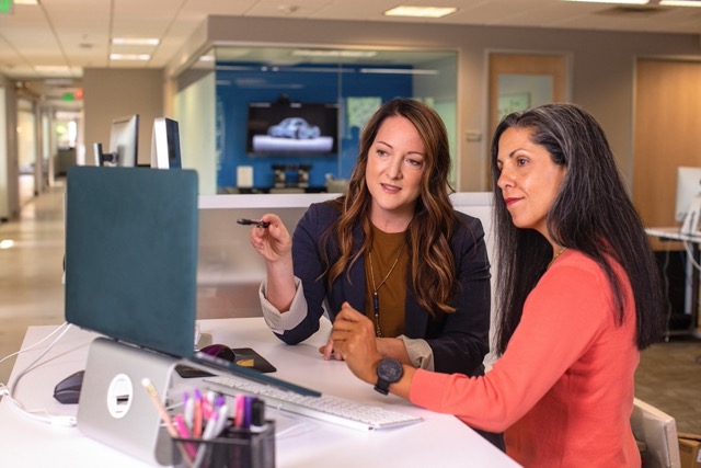 Two people sat at a desk looking at a computer screen