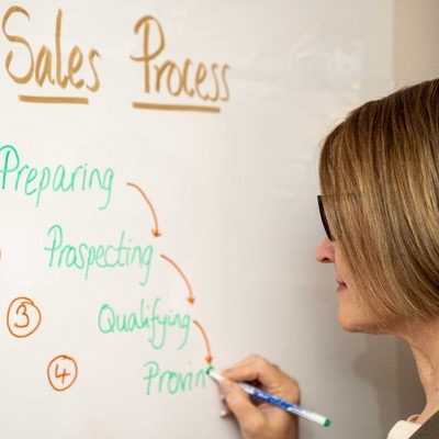 Anna writing a sales process on a whiteboard - part of the sales consulting and coaching process.